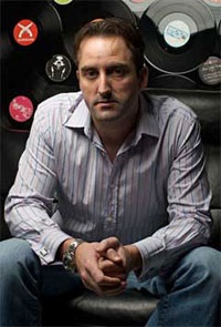 mugshot of Paul Walsh, inexplicably against a background of vinyl records
