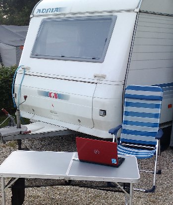 A laptop on a temporary able outside a caravan
