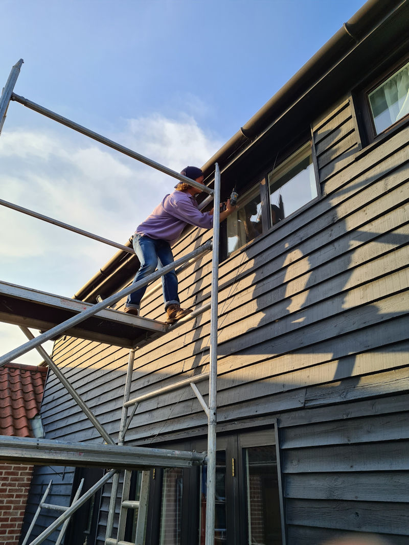 Young man on top of an access tower, drilling a hole
