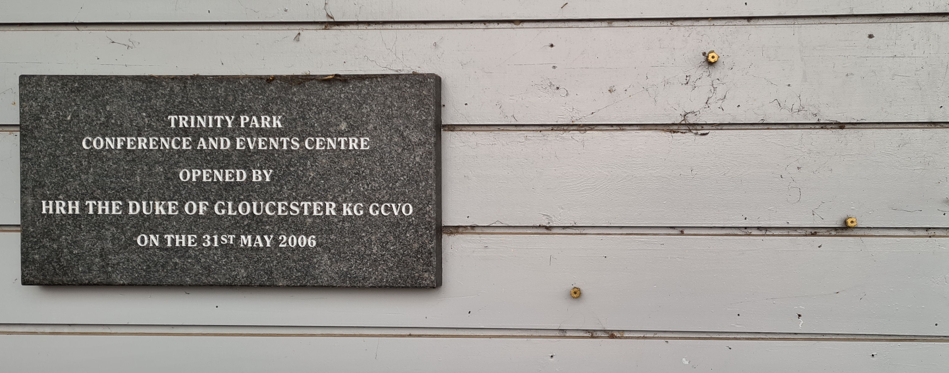 the blank wall where the plaque used to be. Just to the left is the nameplate for the building itself that says: Trinity Park Conference and Events Centre. Opened by HRH The Duke of Gloucester KG GCVO on 31st May 2006