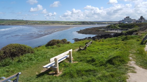Looking landwards along a narrow estuary with sand exposed to the left and rocks to the right.